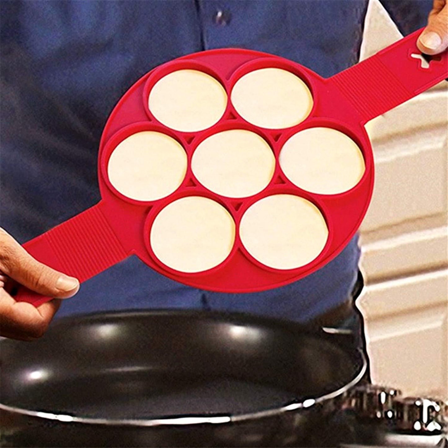 Silicone pancake mold with eggs and pancakes cooking on stovetop